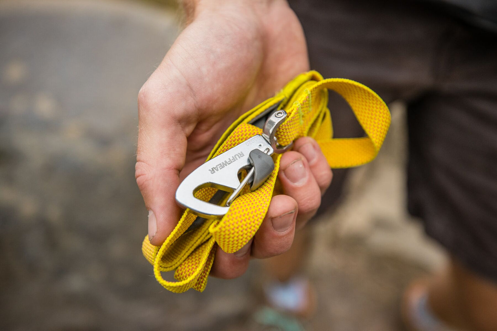 Close-up of a hand holding the Ruffwear Hi & Light Dog Lead in Lichen Green coiled small, showing the lockable Crux Clip